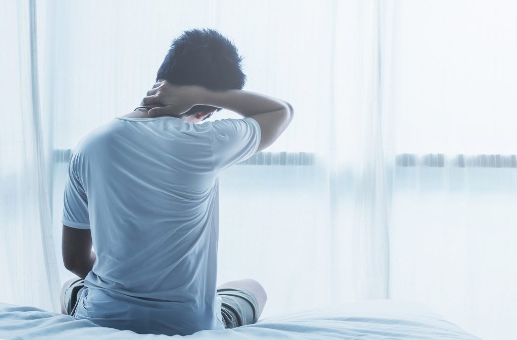 Asian man in bed with neck pain in the morning
