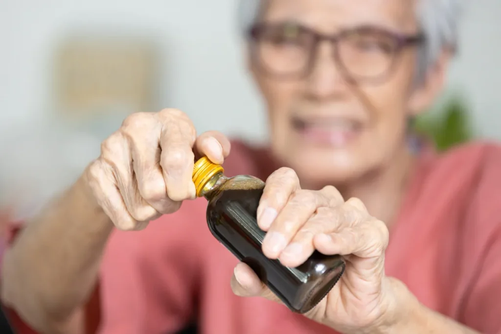Elderly lady trying to open a bottle of ointment